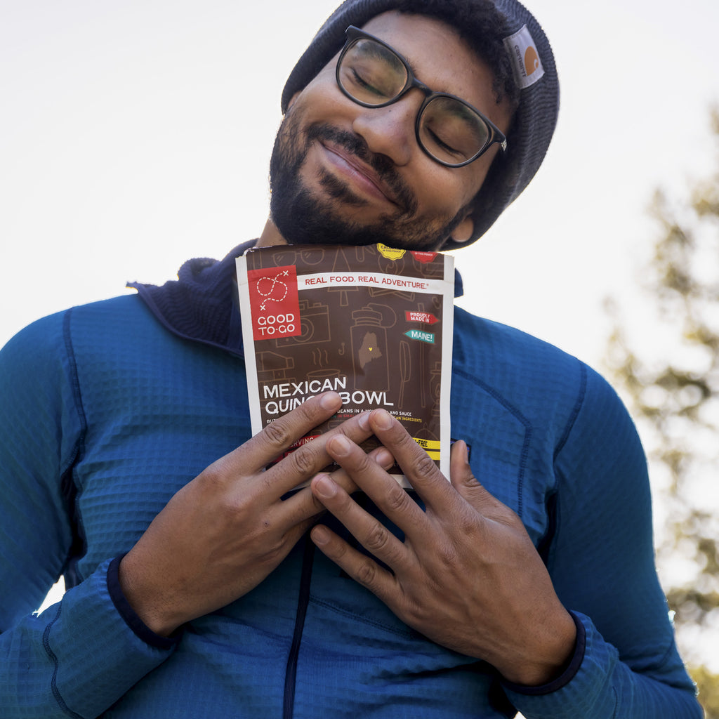 Man lovingly holding a pouch of Good To-Go's Mexican Quinoa Bowl outdoors